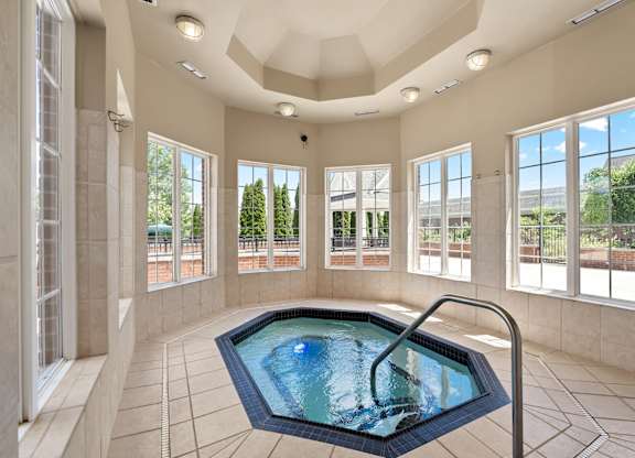 an indoor jacuzzi in a large room with windows