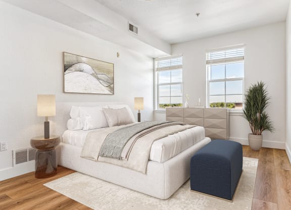 a white bedroom with a bed and a blue ottoman
