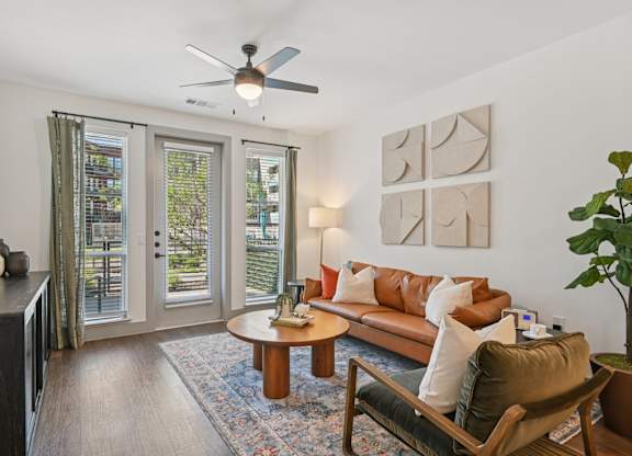 A living room with a brown couch, a coffee table, and a ceiling fan.