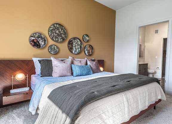 A bedroom with a bed, pillows, and a lamp.