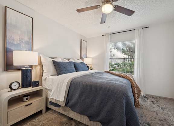 A bedroom with a bed, nightstand, and window.