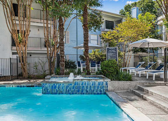 A pool surrounded by trees and chairs.
