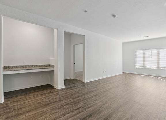 A large empty room with wooden floors and white walls.