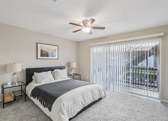 A bedroom with a bed, nightstands, and a ceiling fan.