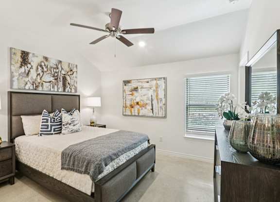 A bedroom with a large bed and a ceiling fan.