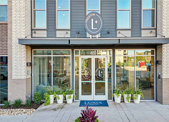 The entrance to a Lululemon store with a blue doormat and potted plants.