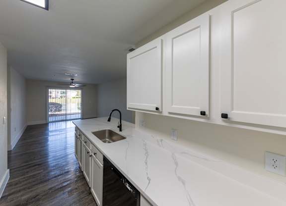 A kitchen with white cabinets and a marble countertop.