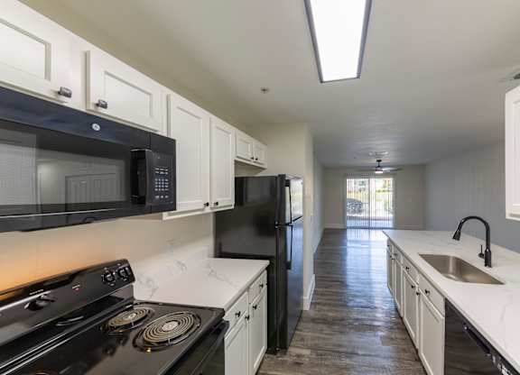 A kitchen with black appliances and white cabinets.