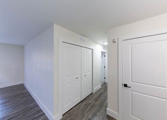 A hallway with white doors and wood floors.