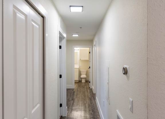 A long white hallway with doors on both sides and a light on the ceiling.