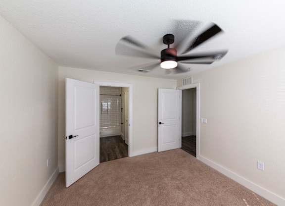 A room with a ceiling fan and two doors.