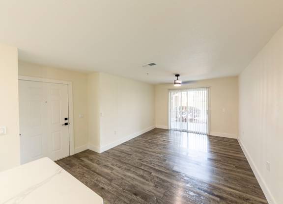 A spacious room with wooden flooring and a white sofa.