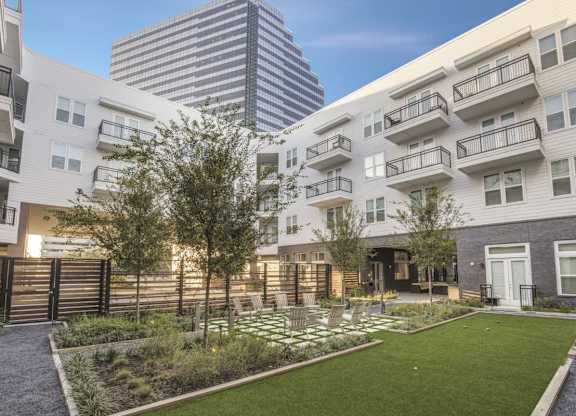 A modern apartment complex with a well-maintained garden in the foreground.