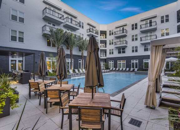 A poolside area with chairs and umbrellas in front of a building.