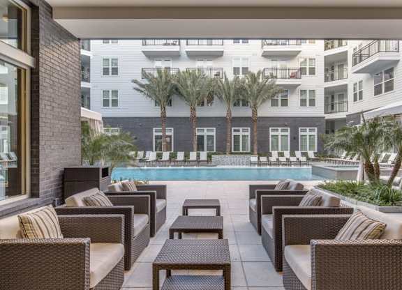 A patio with brown furniture and a pool in the background.