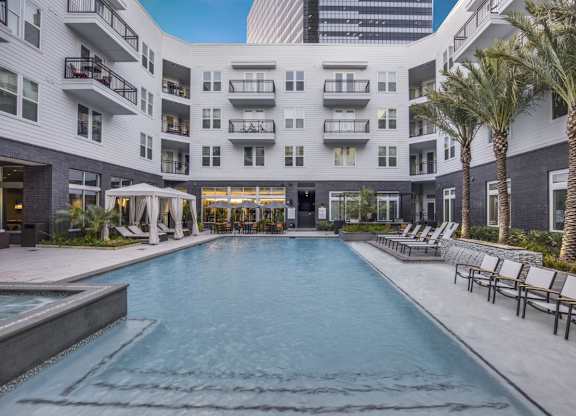 A large swimming pool in front of a building with a white exterior.