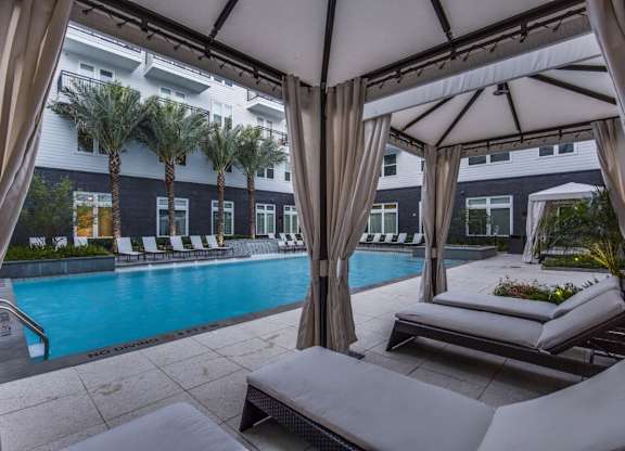 A pool area with sun loungers and a canopy.