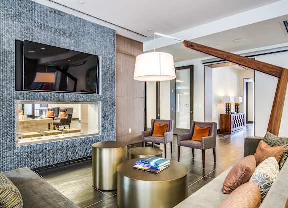 A living room with a grey sofa, a round gold coffee table, and a large mirror on the wall.
