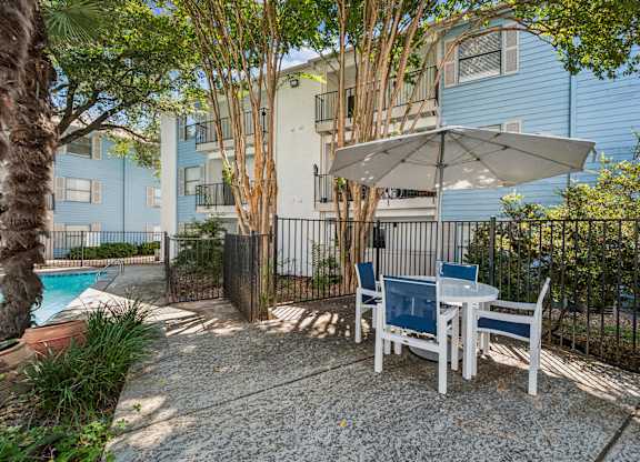 A patio with a table and chairs and an umbrella.