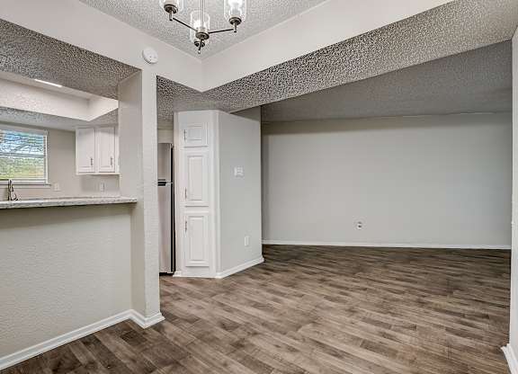 a kitchen and living room with hardwood floors and a chandelier