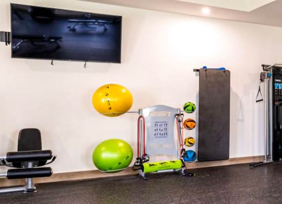 A room with a television, exercise equipment, and a ball.