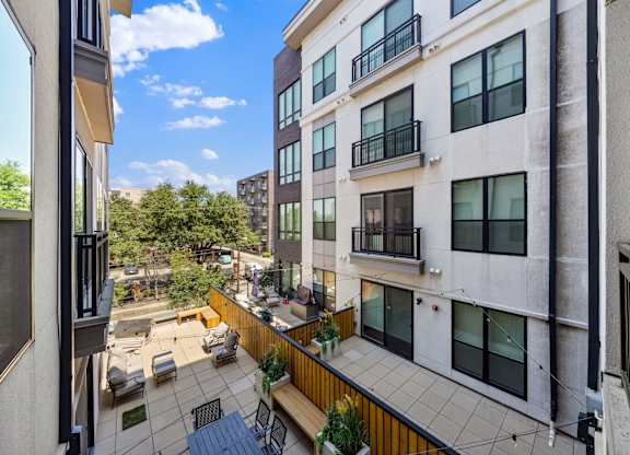 A balcony with a table and chairs overlooks a courtyard.