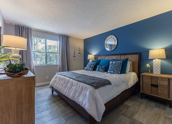 A bedroom with a large bed and a wooden nightstand.