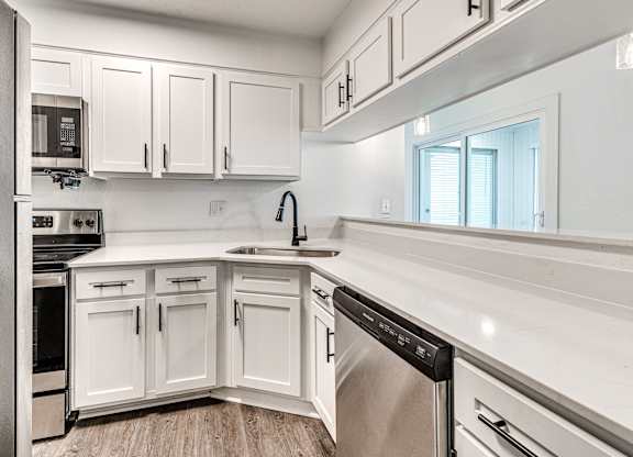 A modern kitchen with white cabinets and stainless steel appliances.