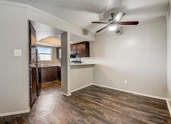 a bedroom with a ceiling fan and a kitchen in the background