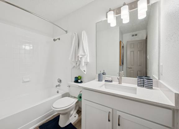 A white bathroom with a toilet, sink, and mirror.