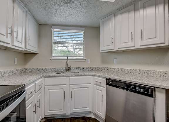 a kitchen with white cabinets and granite counter tops