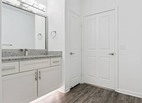 A white bathroom with a vanity and a door.