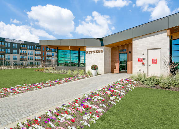 A gym building with a flower bed in front.