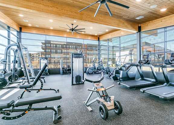 A gym with a variety of equipment including treadmills, weights, and a stationary bike.