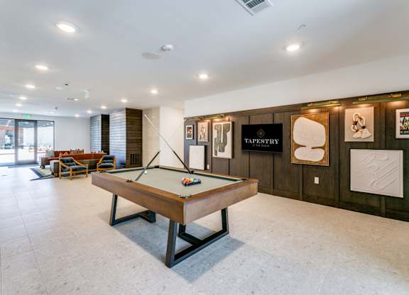 A pool table in a room with a sign that says "TAPESTRY".