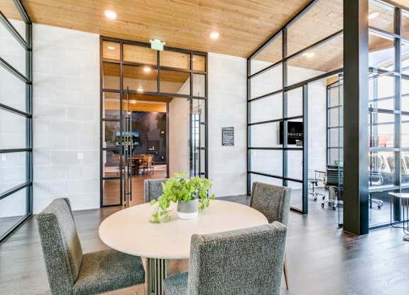 A round table with four chairs around it in a room with a glass wall.