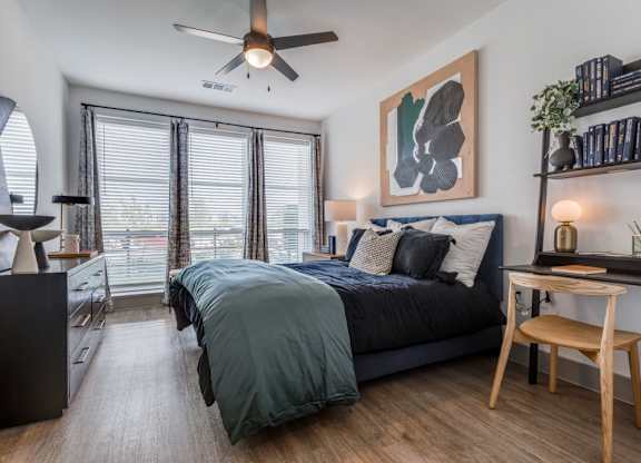 A bedroom with a bed, a chair, and a ceiling fan.