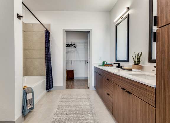 A bathroom with a white tub, a sink, and a mirror.