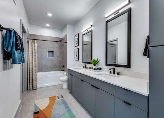 A modern bathroom with a large mirror and a white sink.