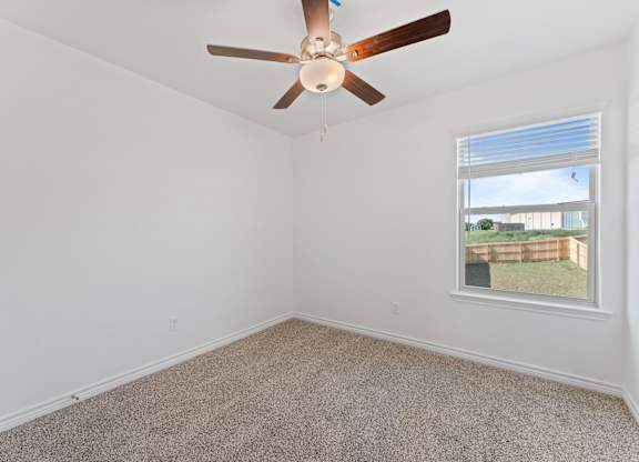 an empty room with a ceiling fan and a window