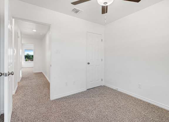 an empty room with white walls and carpet and a ceiling fan