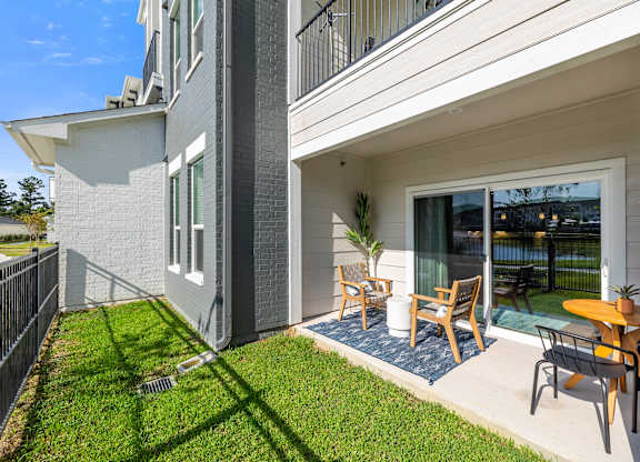 A modern house with a grey and white exterior and a patio with chairs and a table.