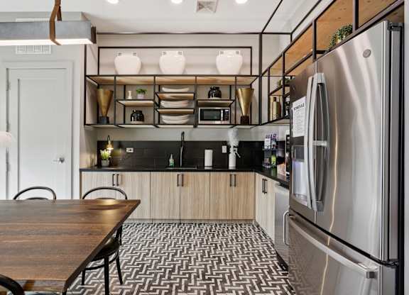 A modern kitchen with a wooden table and stainless steel appliances.