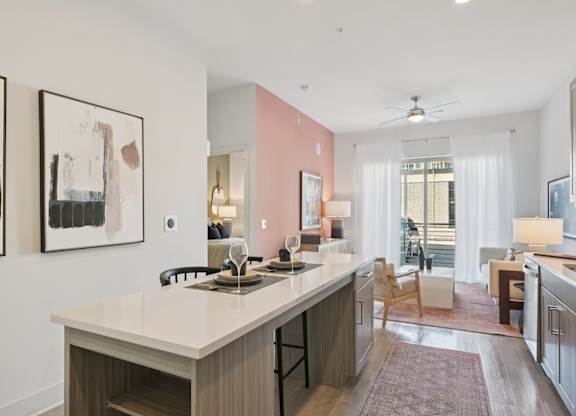 A kitchen with a white countertop and a pink wall.