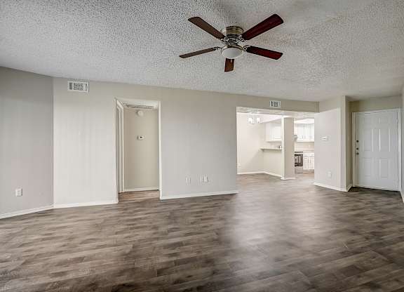 an empty living room with a ceiling fan