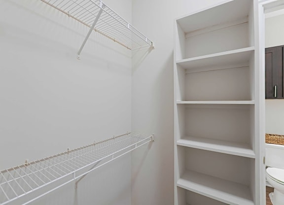a walk in closet with shelves and a toilet in it