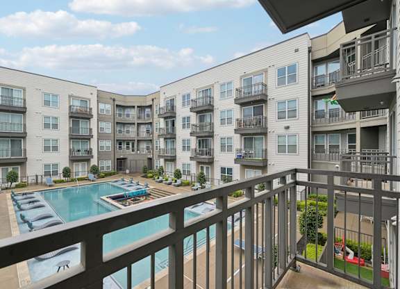 A view of a pool and apartment buildings from a balcony.