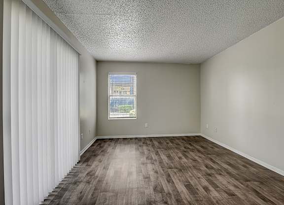an empty living room with a window and curtains