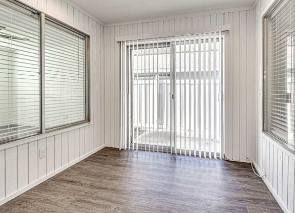 A room with wooden floors and white walls with a sliding glass door.