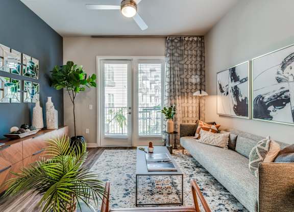A living room with a couch, a table, and a plant.